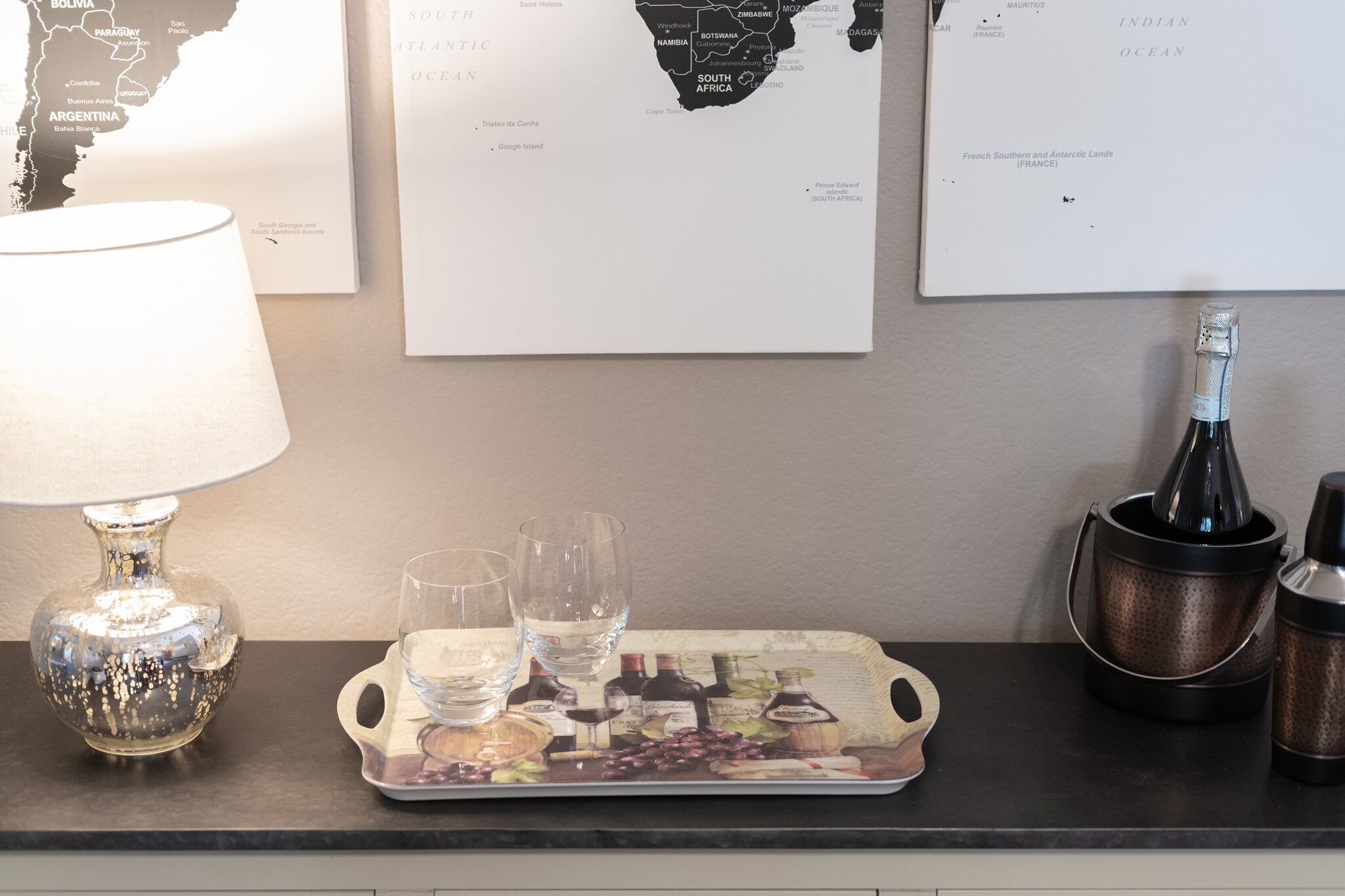 Ein Tisch mit einem Tablett, Gläsern, einer Flasche und einer Lampe.