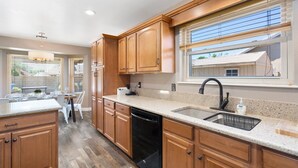 A modern kitchen with wooden cabinets, a granite countertop, and a black dishwasher. - HUGE, heated pool. Family friendly, toys for all!  Big & beautiful backyard!  (Mesa)