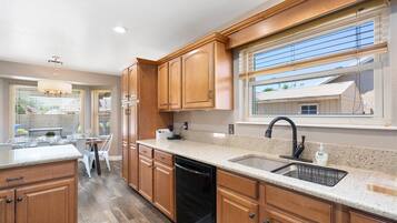 A modern kitchen with wooden cabinets, a granite countertop, and a black dishwasher.