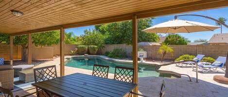 A covered patio with a pool, outdoor furniture, and a basketball hoop.
