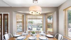 A dining area with a wooden table set for six, white chairs, and a chandelier. - HUGE, heated pool. Family friendly, toys for all!  Big & beautiful backyard!  (Mesa)