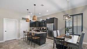A modern kitchen with dark cabinets, a central island, and pendant lighting. - Unique and Secluded home, traffic-free and quite (El Paso)
