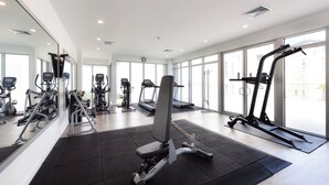 A modern gym with various exercise equipment, large windows, and a clean, spacious layout. - Villa Walking Distance to Eagle Beach (Noord)