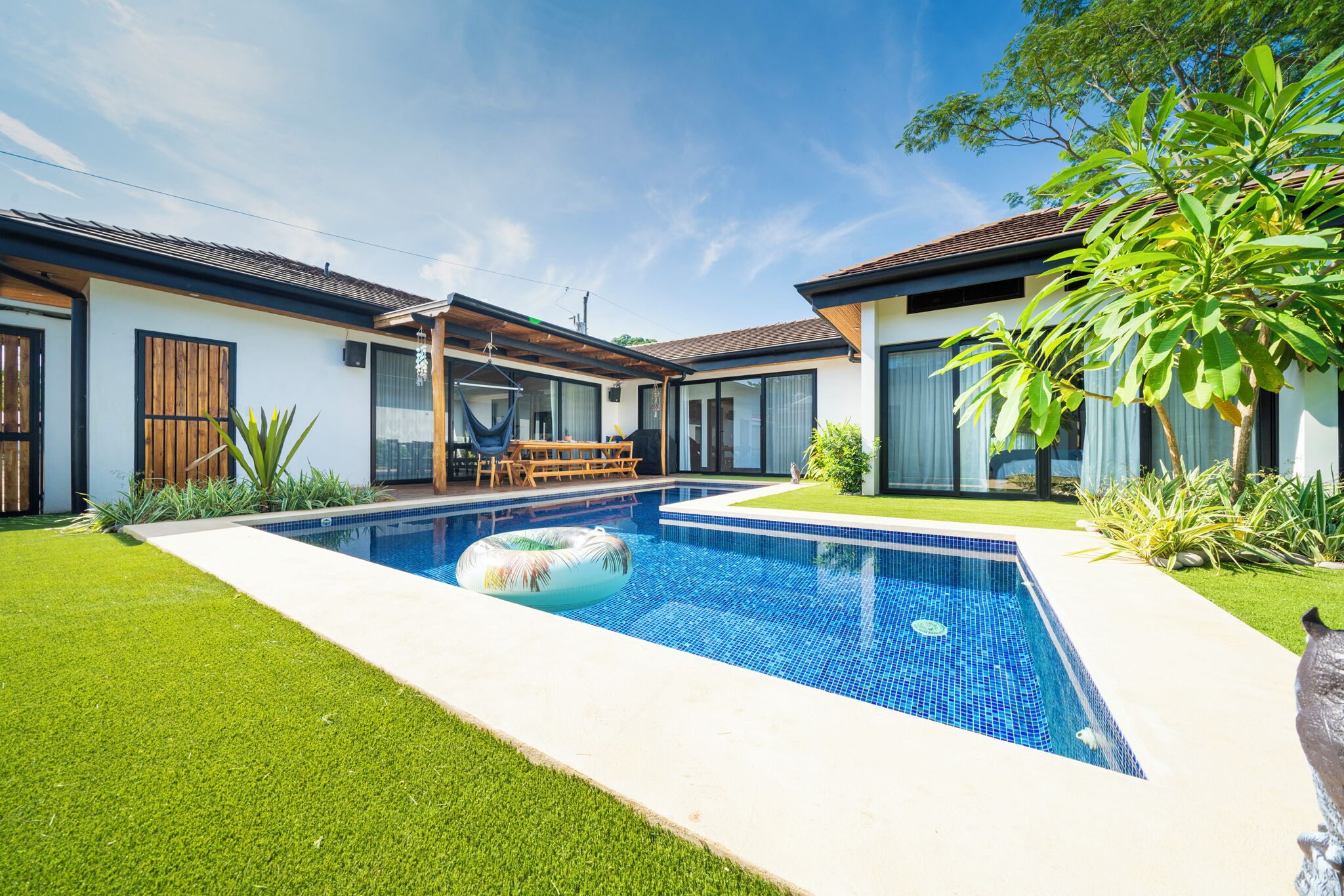 A modern house with a swimming pool, a wooden deck, and a well-maintained lawn.
