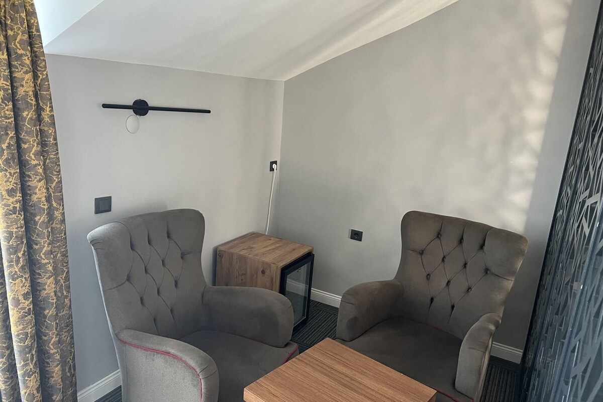 Una habitación con dos sillones, una mesita de madera y una mesa de centro.