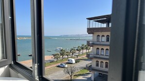 A view from a window overlooking a marina with boats, a parking area, and a building with multiple balconies. - Cepnis Hotel (Atakum)