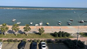 A coastal view with boats docked along the shore, a parking area with cars, and a clear sky. - Cepnis Hotel (Atakum)