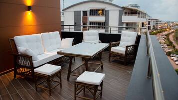 Una terraza en la azotea con un conjunto de sofás, una mesa y sillas.