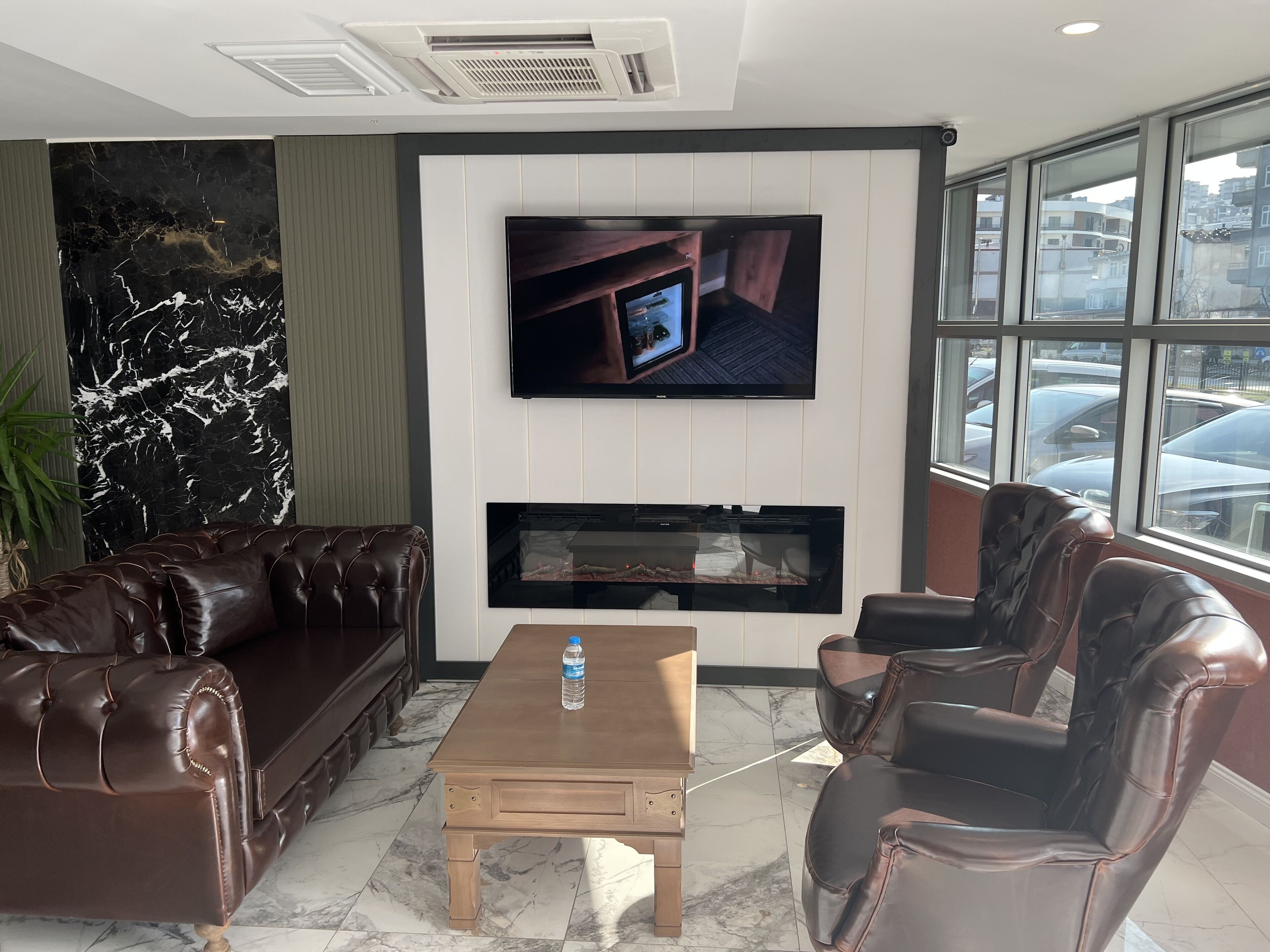 Una sala de estar moderna con un sofá de cuero, una mesa de centro, un televisor de pantalla plana montado en la pared y una chimenea.