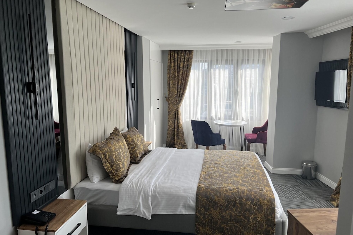 Una habitación de hotel con cama, mesita de noche, silla y un pequeño escritorio.