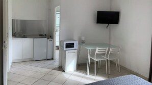 A compact kitchen with white cabinets and a small refrigerator, a dining area with a table and chairs, and a flat-screen TV mounted on the wall. - The countryside 5 minutes from Tours (Fondettes)
