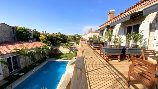 Un área junto a la piscina con terraza de madera, sillones de descanso y una pileta.