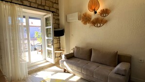 Una sala de estar con un sofá color beige, un tapete estampado, una mesa de centro de madera y una lámpara de pared.