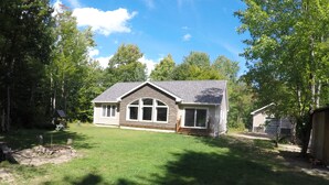 A single-story house with a sloped roof, large windows, and a front porch. - MODERN COTTAGE GETAWAY (Barry's Bay)