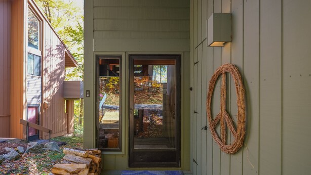 A wooden building with a glass door, a peace sign decoration, and a wooden staircase leading to the entrance.