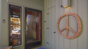 A house entrance with a glass door, a peace sign decoration, and a blue mat on the steps.