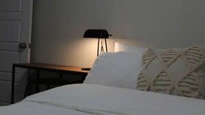 A bedroom with a bed, a bedside table, and a floor lamp. - 3BR Sunshine basement w separate entrance Waterloo (Waterloo)