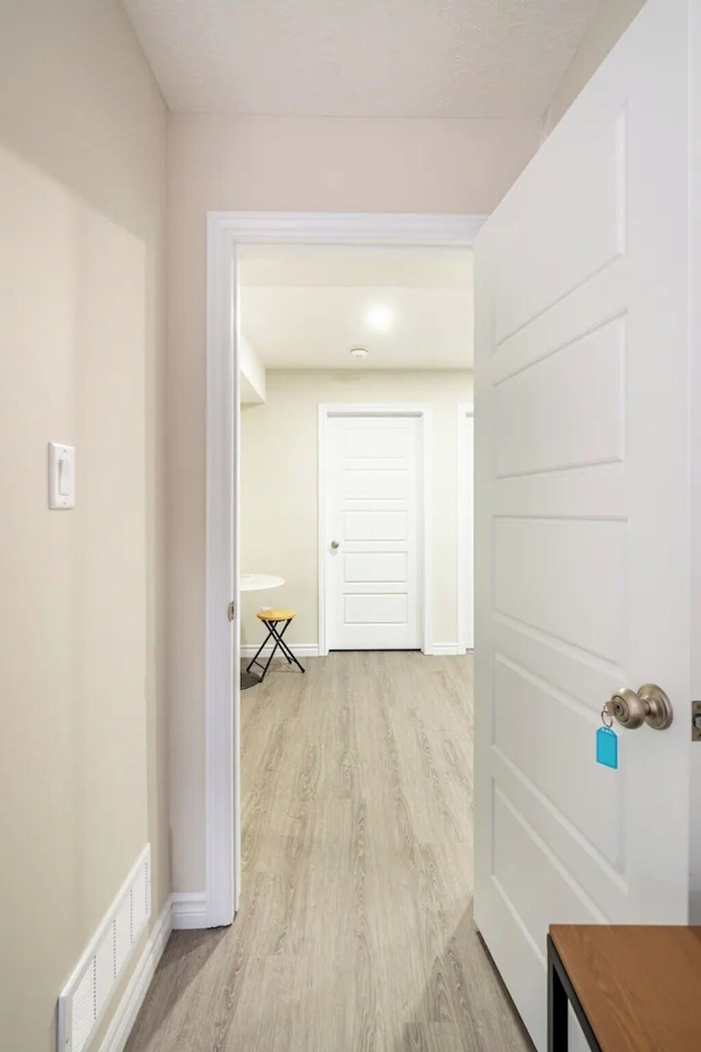 A hallway with a white door, a small table with a chair, and a radiator on the wall.