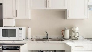 A modern kitchen with white cabinets, a built-in microwave, a coffee maker, and a sink. - 3BR Sunshine basement w separate entrance Waterloo (Waterloo)