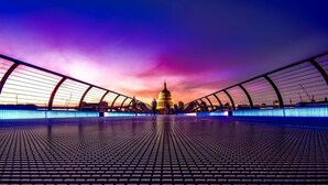 A bridge with a patterned walkway leading to a domed building.