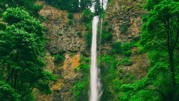 A waterfall cascading down a rocky cliff, with a bridge spanning across the water.
