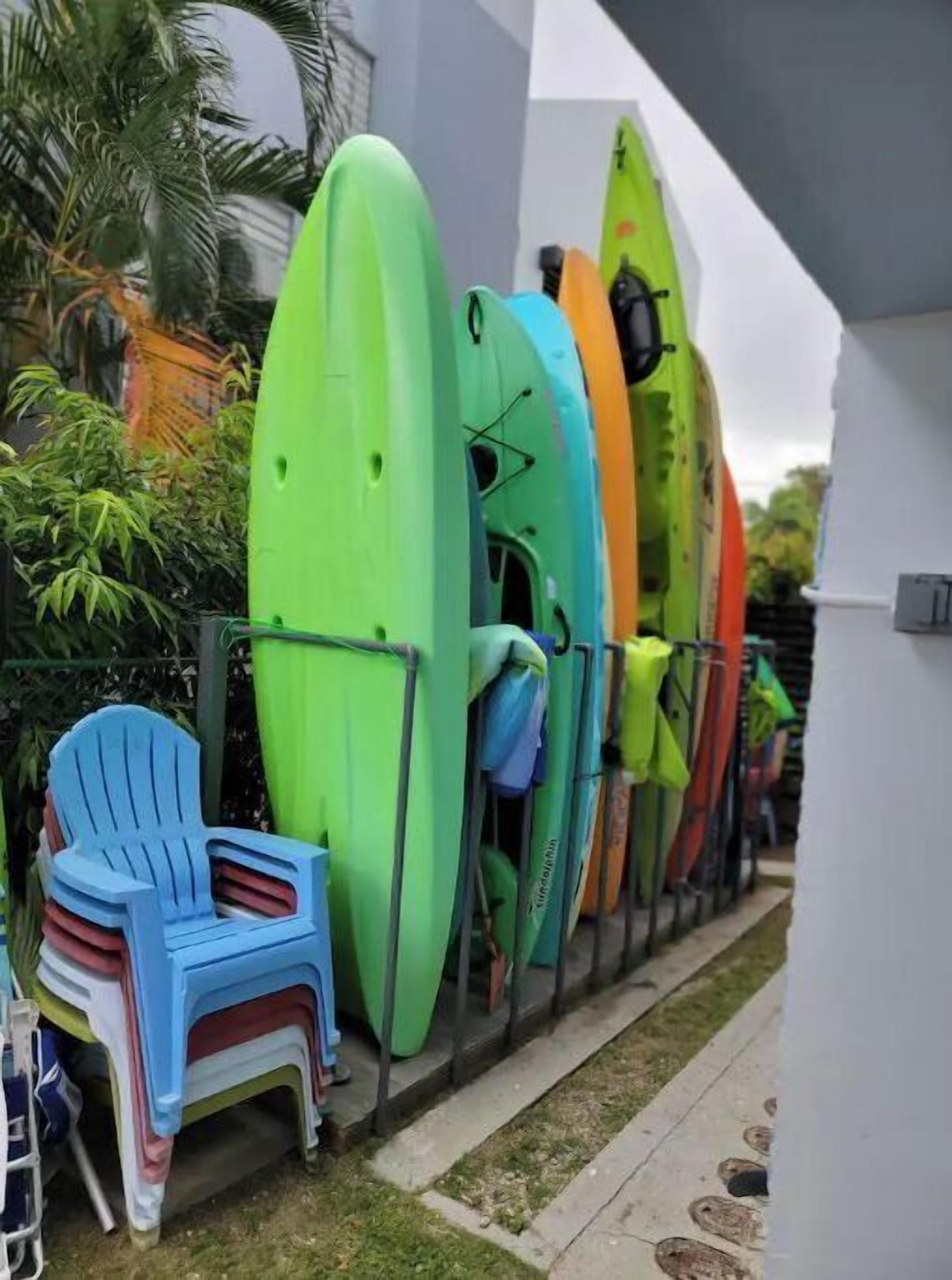 A row of surfboards leaning against a wall, a blue chair, and a small table.