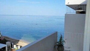 Un balcón con vista al mar, una planta en maceta y una silla de madera.