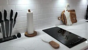 Una cocina con azulejos tipo metro blancos, estantes de madera y diversos utensilios de cocina.