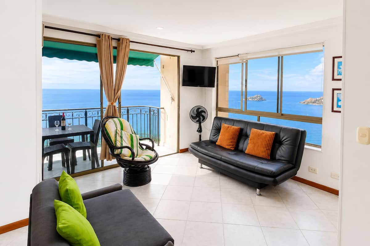 Un salon comprenant un canapé, une table à manger, une chaise et un balcon avec vue sur la mer.