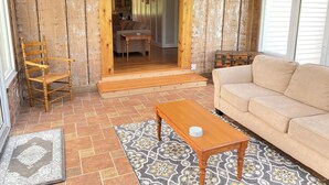 Une pièce chaleureuse avec une chaise en bois, un canapé, un tapis à motifs et une table en bois.