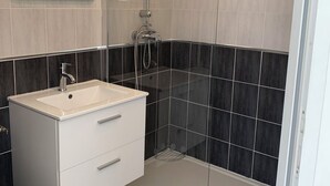 A modern bathroom with a glass-enclosed shower, a white vanity with a sink, and two wall-mounted mirrors. - The charm of Touraine (Fondettes)