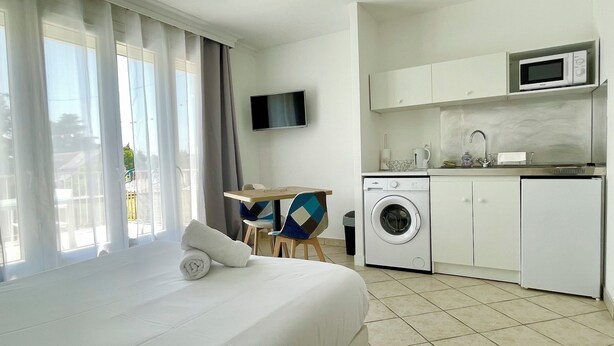 A hotel room with a bed, a washing machine, a microwave, and a TV. - The charm of Touraine (Fondettes)