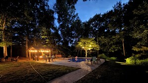 A backyard with a pool, patio furniture, and a gazebo with string lights. - Mountain Cabin in Town (Wake Forest)