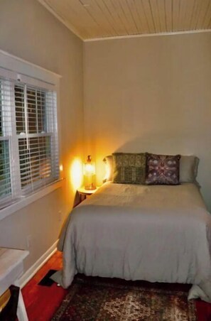 Cozy retreat with a single bed, window, and wall-mounted lamp.