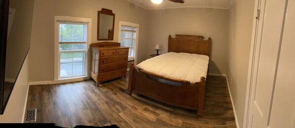 A bedroom with a wooden bed, a dresser, and a mirror. There are two windows with blinds. - 1st Class Rentals 1 Bedroom Apt. at Church Street (Oneonta)