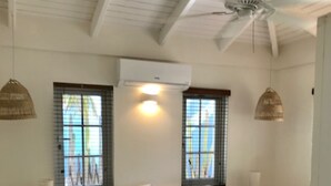 Une chambre à coucher comprenant un lit, deux tables de chevet, un appareil de climatisation et deux fenêtres équipées de stores.