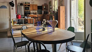 Eine geräumige Küche mit Holzausstattung, einem Esstisch mit Stühlen und einem großen Fenster für natürliches Licht.