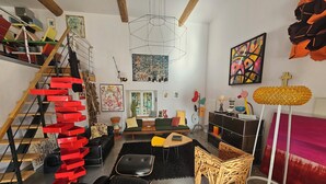 Ein modernes Wohnzimmer mit Treppe, einem grünen Sofa, einem Holzstuhl und einer Stehlampe.