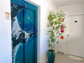 Un pasillo con un gran mapa azul de una zona costera, una planta en maceta y un extintor.