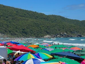 A beach with colorful umbrellas and people swimming in the water. - Bella Catarina Bombinhas (Bombinhas)