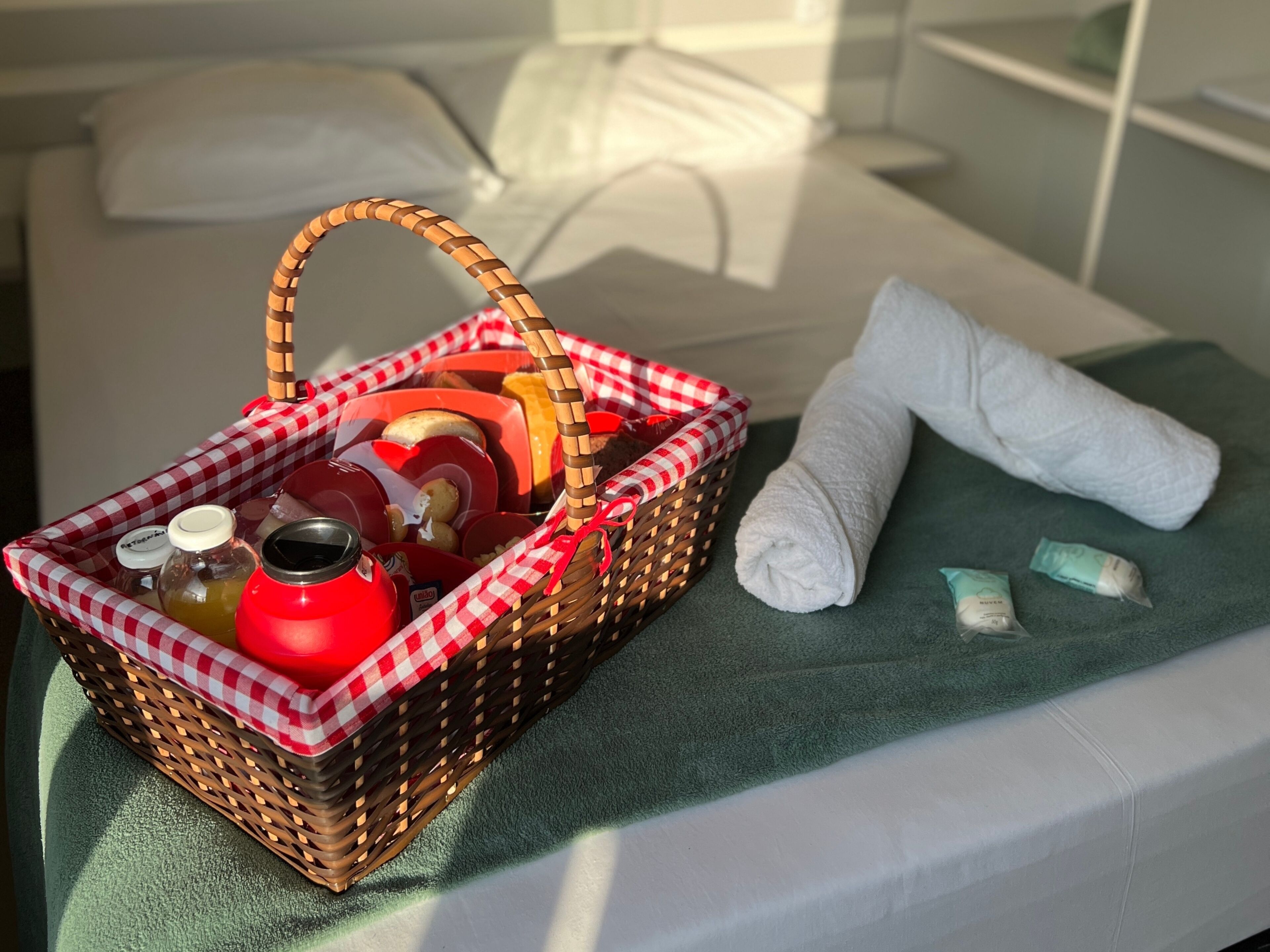 Una cesta de mimbre con alimentos y una toalla enrollada sobre la cama.
