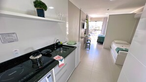A modern kitchen with a black countertop, a built-in dishwasher, and a small dining area with a table and chairs. - Bella Catarina Bombinhas (Bombinhas)