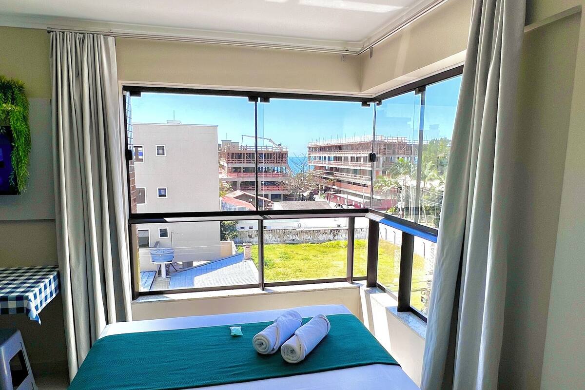 A hotel room with a large bed, a view of a construction site, and a balcony with a railing.