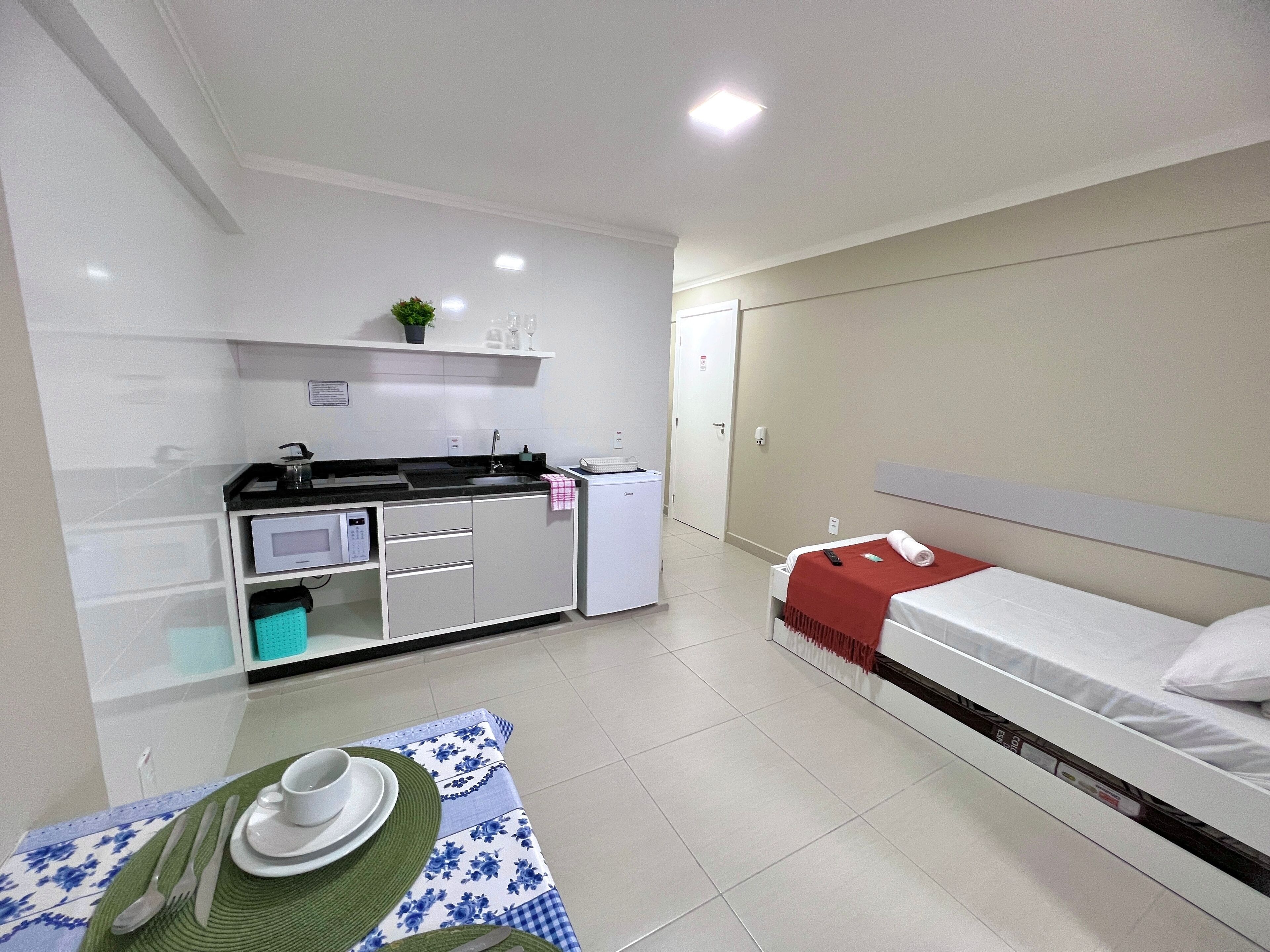 Una habitación de hotel pequeña con kitchenette, una cama individual y un comedor.