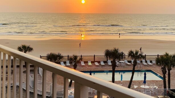 A beach view with a pool and lounge chairs. - Sea Dip Resort Studios (Daytona Beach)