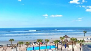 A beach view with a pool, palm trees, and a gazebo. - Sea Dip Resort Studios (Daytona Beach)