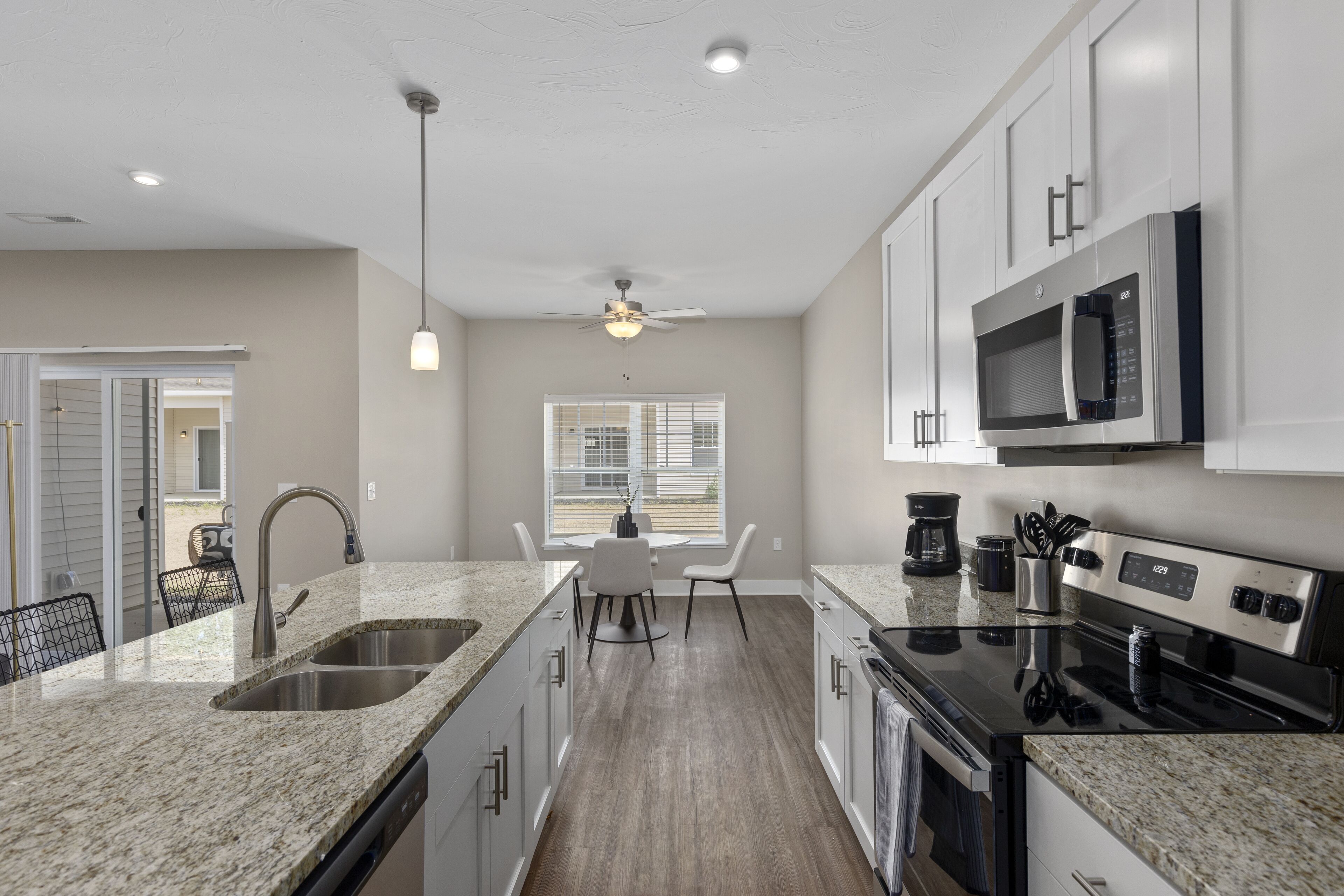 A modern kitchen with granite countertops, stainless steel appliances, and a dining area with a table and chairs.