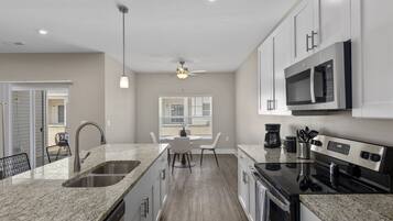 A modern kitchen with granite countertops, stainless steel appliances, and a dining area with a table and chairs.