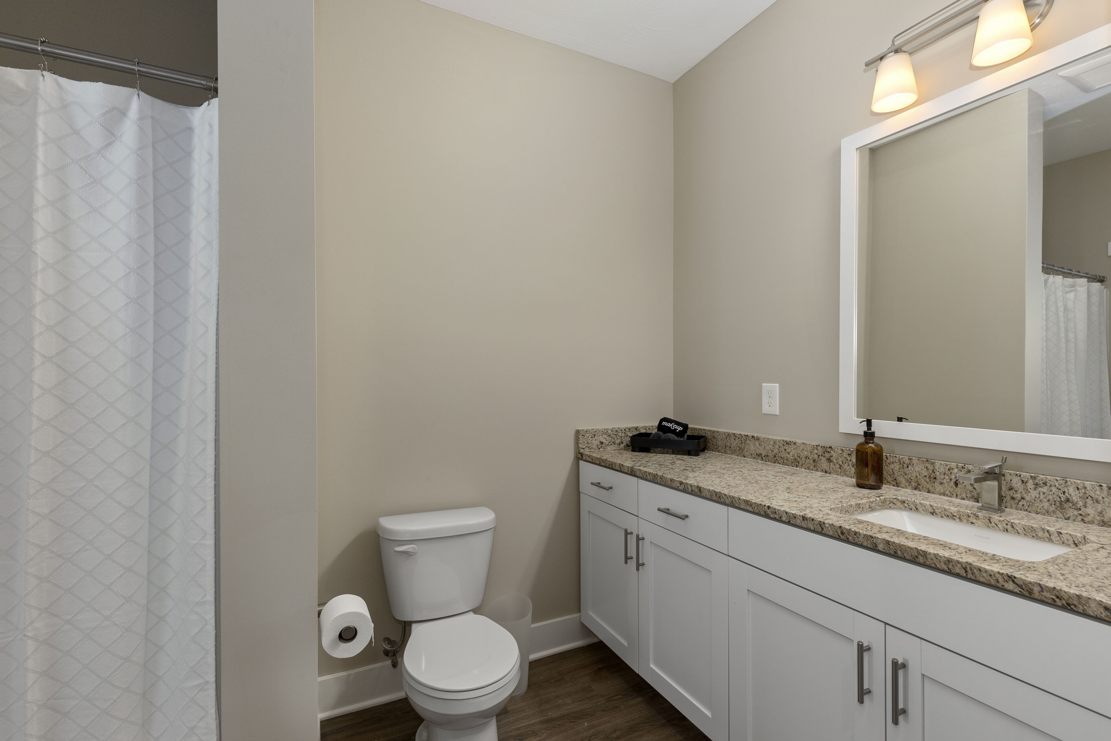 A bathroom with a toilet, sink, and mirror.