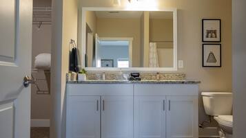 A modern bathroom with a vanity, a toilet, and a shower area.